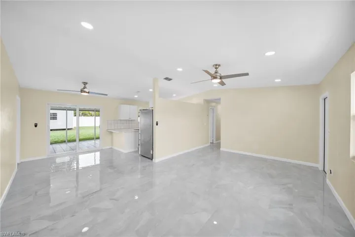 Unfurnished living room featuring a ceiling fan, light marble finish flooring, and recessed lighting