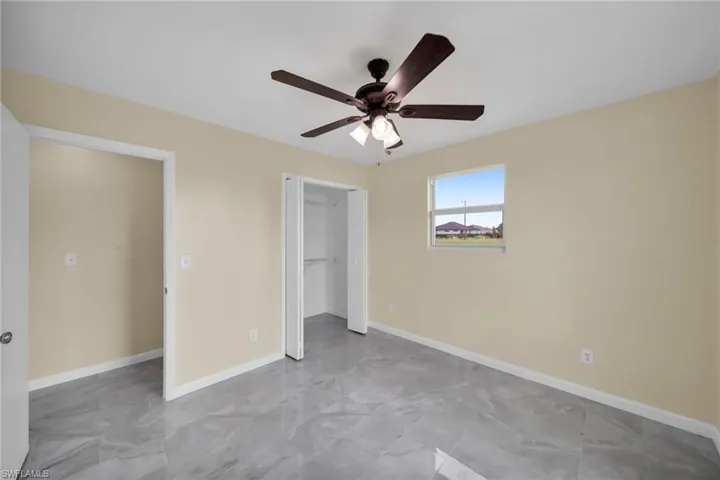 Unfurnished bedroom with marble finish floors, a ceiling fan, and a closet
