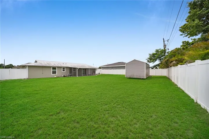 Fenced backyard with a storage unit and a sunroom