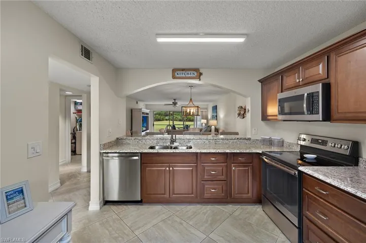 Kitchen with pendant lighting, sink, stainless steel appliances, and a textured ceiling