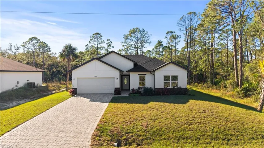 View of front of home with central AC unit, a garage, and a front yard