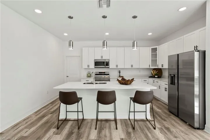 Kitchen featuring stainless steel appliances, white cabinetry, and LVP flooring.