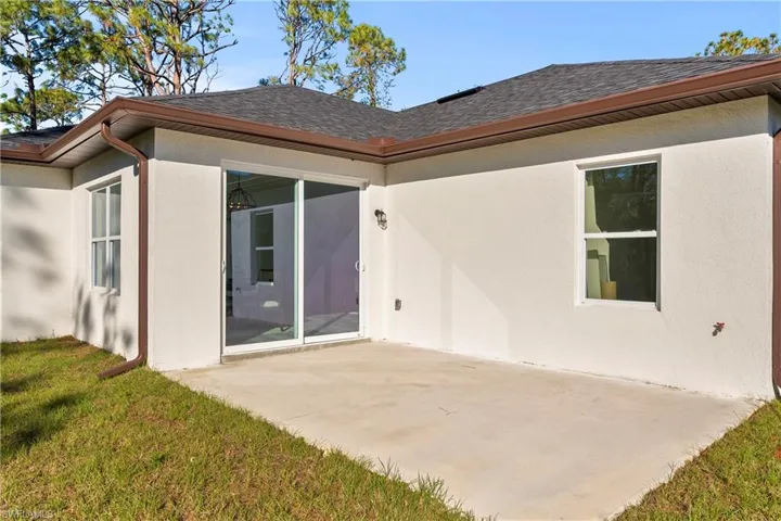 Back of property with a patio and a lawn