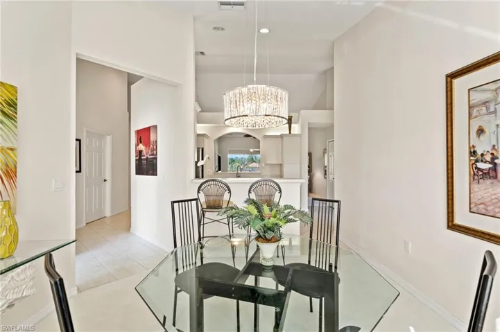 Dining area featuring a clear glass tabletop, a contemporary chandelier, and high vaulted ceilings