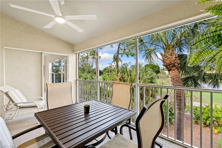 Screened lanai featuring a vaulted ceiling with a modern ceiling fan, textured walls, and tile flooring