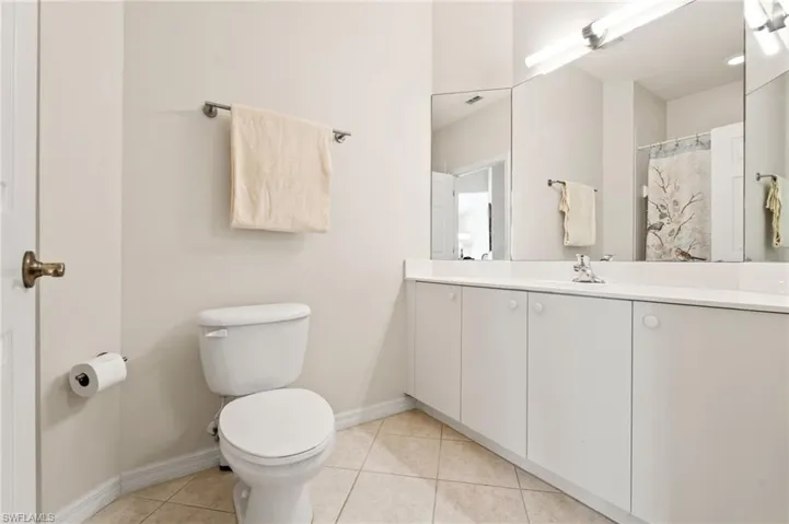 Bathroom featuring a white vanity with integrated sink, a large wall-mounted mirror, and tile flooring