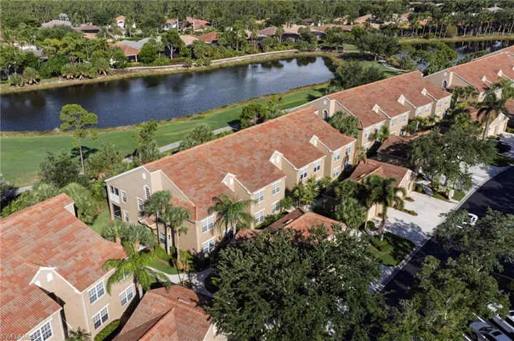 Mediterranean-style townhomes featuring terra cotta roofs, stucco exteriors, and mature tropical landscaping