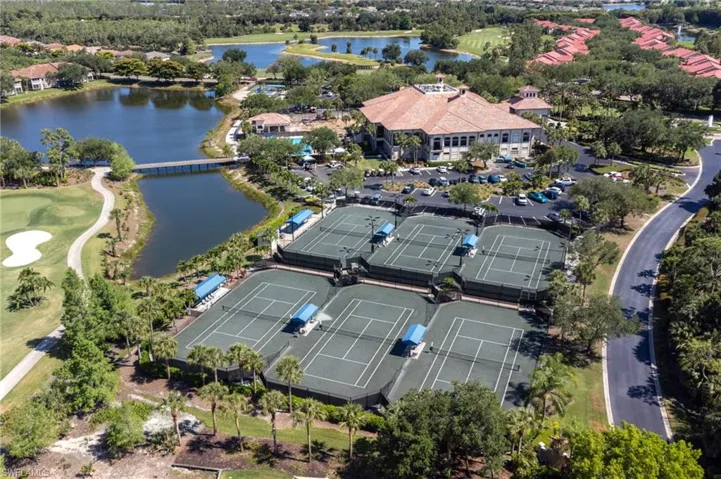 Expansive tennis court complex featuring multiple courts, shaded seating areas, and surrounding landscaping