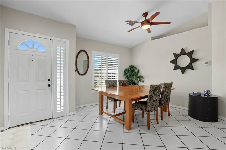 Dining space featuring lofted ceiling, light tile patterned flooring, and a ceiling fan