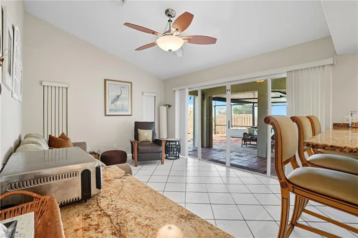 Living room featuring a ceiling fan, vaulted ceiling, and light tile patterned floors