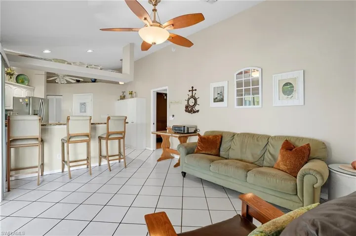 Living room with a ceiling fan, light tile patterned floors, recessed lighting, and a high ceiling