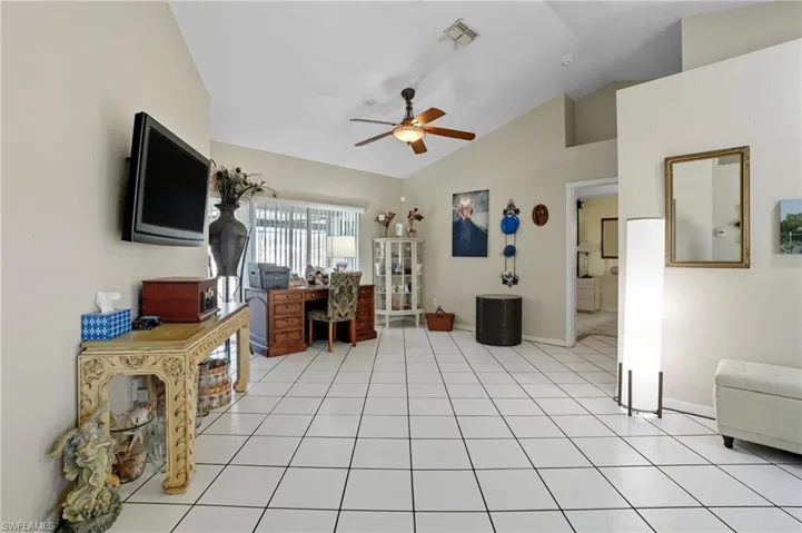 Office area with vaulted ceiling, light tile patterned floors, and a ceiling fan