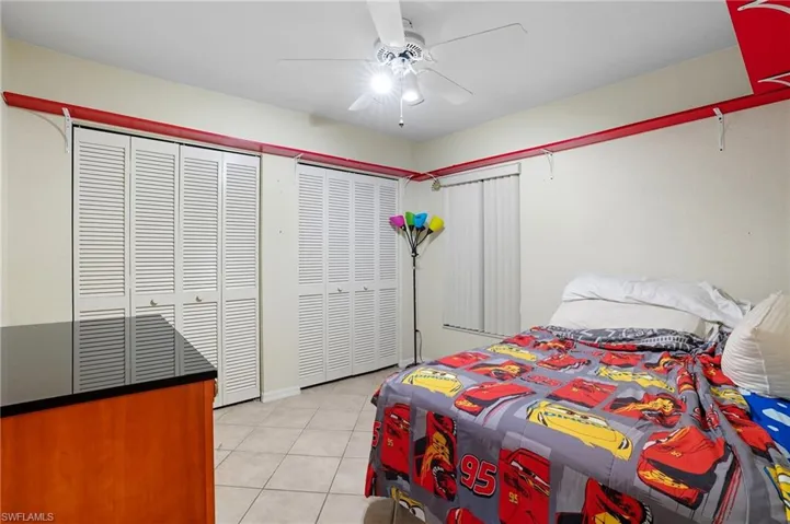 Bedroom featuring multiple closets, light tile patterned floors, and a ceiling fan