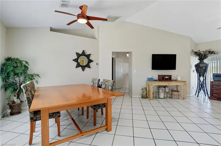 Dining room with a ceiling fan, light tile patterned flooring, and high vaulted ceiling