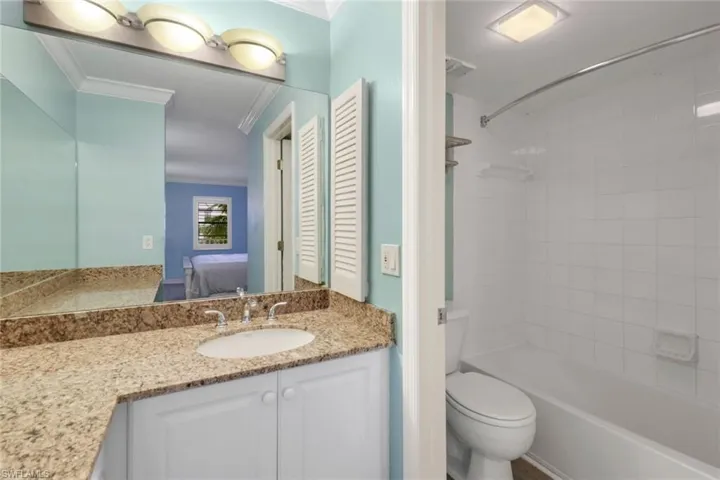 Full bathroom featuring toilet, tiled shower / bath, vanity, and ornamental molding