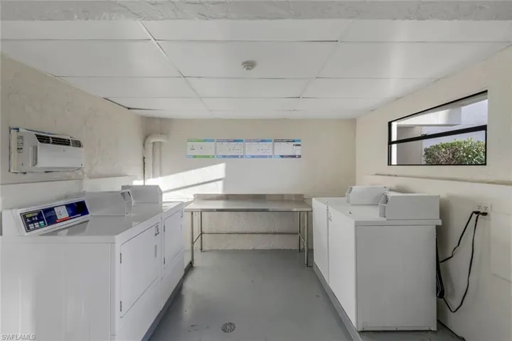 Clothes washing area featuring washer and dryer and a wall mounted air conditioner