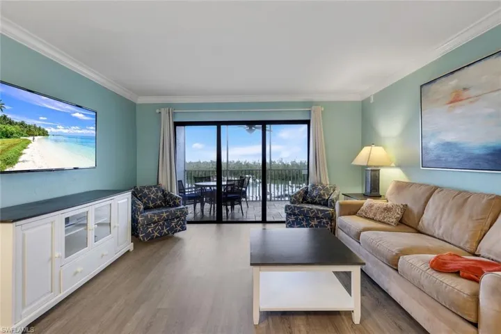 Living room with light hardwood / wood-style flooring, crown molding, and a water view