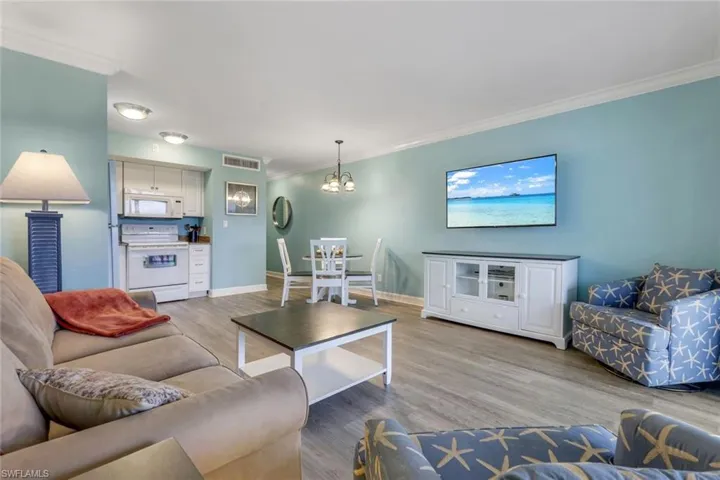 Living room featuring crown molding, light wood-type flooring, and a chandelier