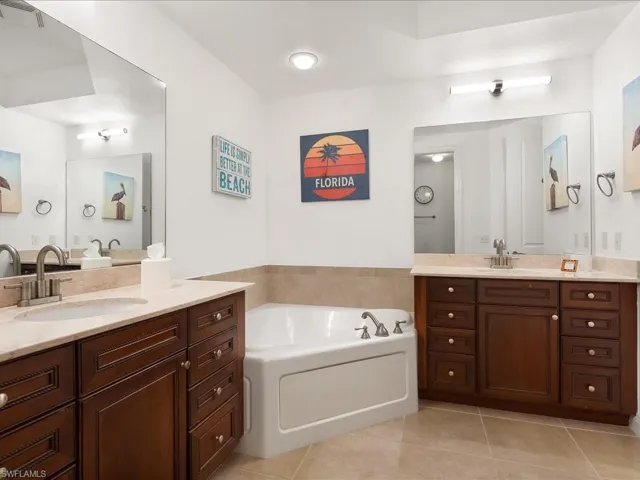 Bathroom with two vanities, a garden tub, and light tile patterned floors