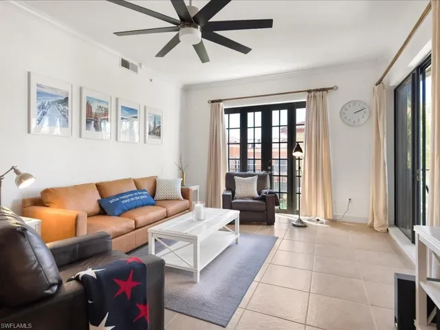 Living room with french doors, ornamental molding, light tile patterned flooring, and a ceiling fan