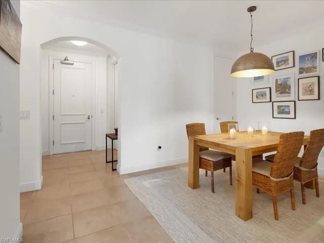 Dining space featuring arched walkways, crown molding, and light tile patterned floors