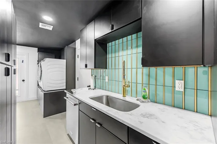 Separate Butlers Pantry off the Kitchen featuring sink, washer / clothes dryer, dishwasher, and light stone counters