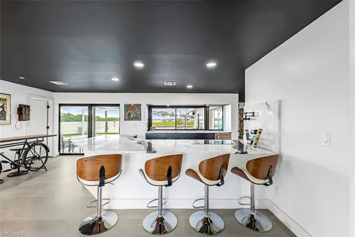 Kitchen featuring stovetop, light stone countertops, a breakfast bar, and kitchen peninsula