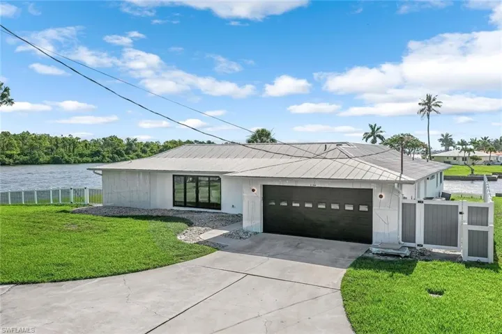 View of front of home featuring a garage, a water view, and a front lawn