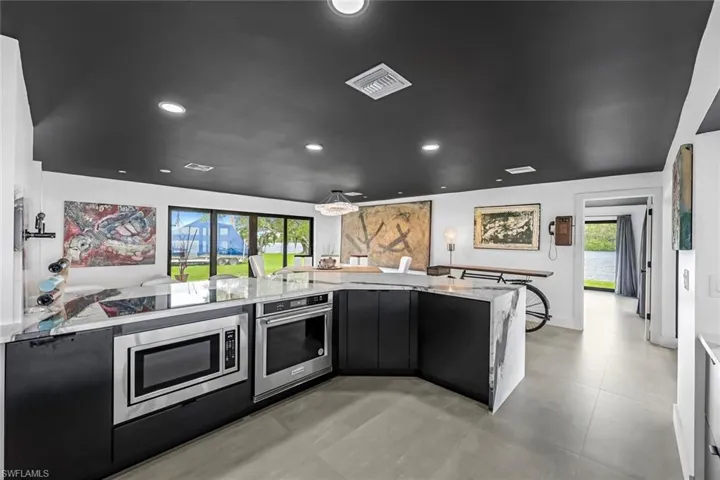 Kitchen featuring a healthy amount of sunlight, kitchen peninsula, light tile floors, and stainless steel appliances