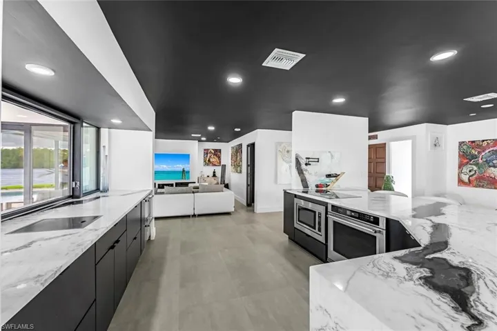 Kitchen with light stone countertops, stainless steel appliances, and light tile floors