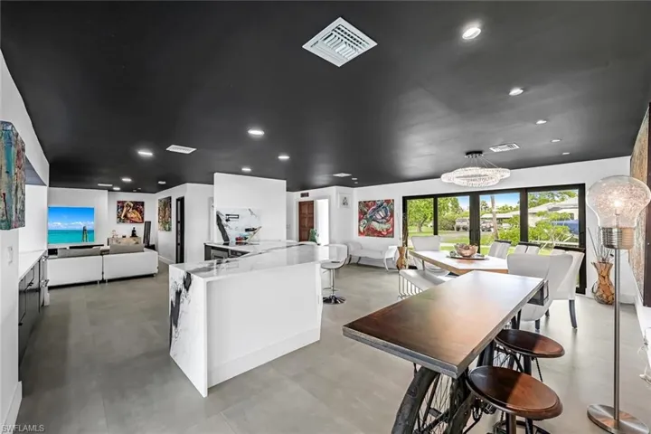 Kitchen with white cabinetry, kitchen peninsula, pendant lighting, and light stone countertops