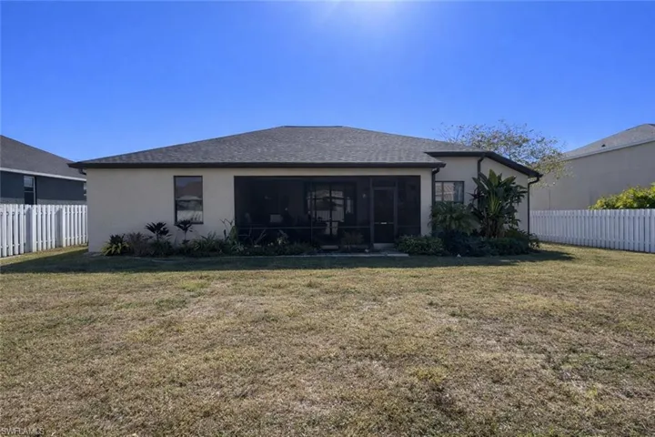 Back of house with a sunroom, stucco siding, and a shingled roof