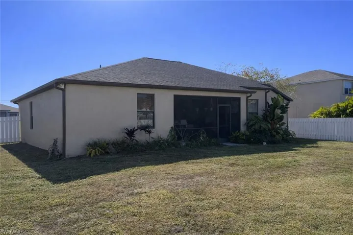 Back of house featuring stucco siding, a sunroom, and roof with shingles