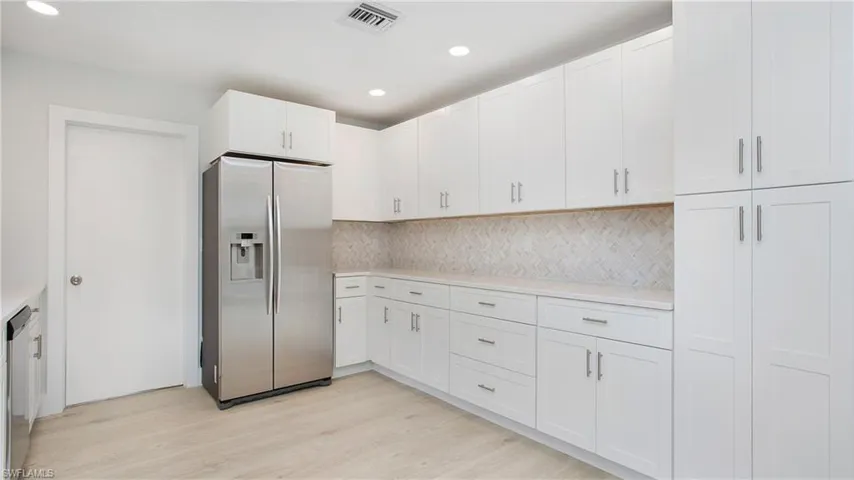 Kitchen with white cabinetry, backsplash, stainless steel fridge with ice dispenser, and light hardwood / wood-style floors