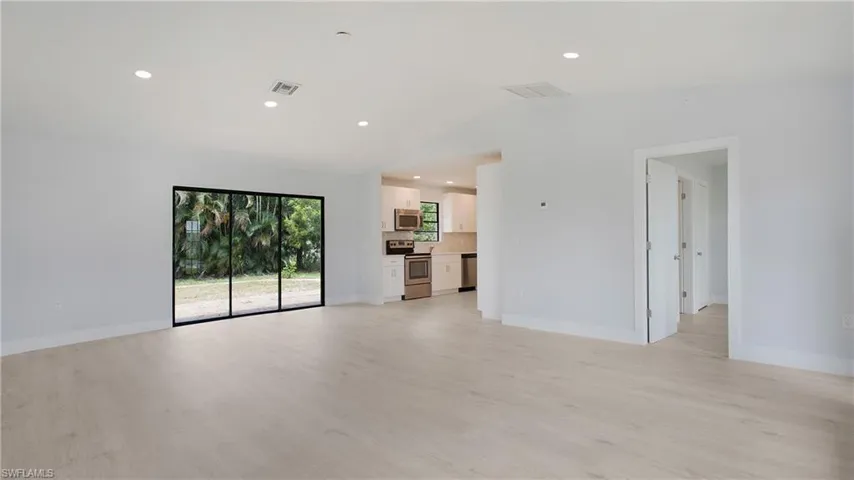 Unfurnished living room with light wood-type flooring and lofted ceiling