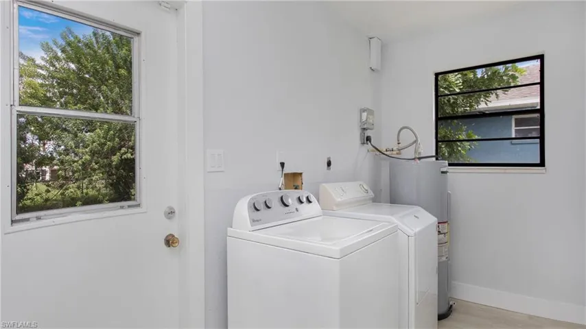 Laundry room featuring washing machine and dryer, electric water heater, and light wood-type flooring