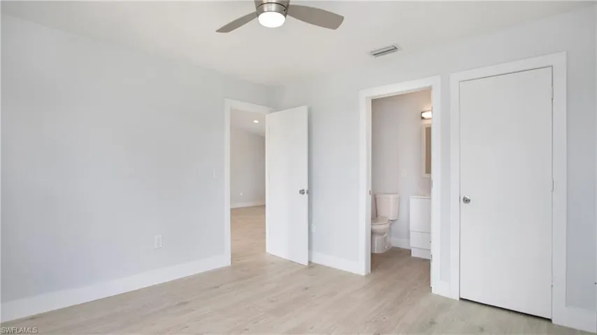 Unfurnished bedroom with ceiling fan, ensuite bathroom, and light hardwood / wood-style flooring