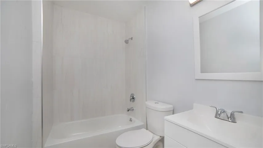 Full bathroom featuring tiled shower / bath combo, vanity, and toilet