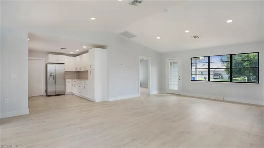 Unfurnished living room featuring lofted ceiling and light hardwood / wood-style floors