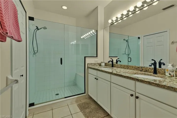 Full bath with double vanity, a stall shower, and light tile patterned floors
