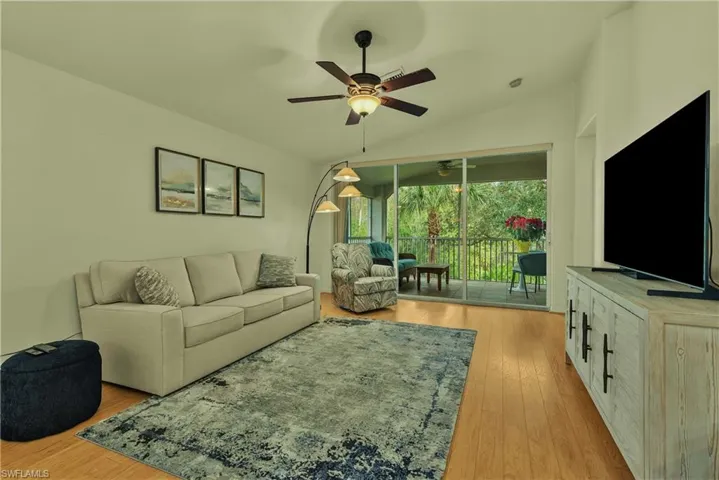 Living area with vaulted ceiling, light wood-style floors, ceiling fan, and a sunroom