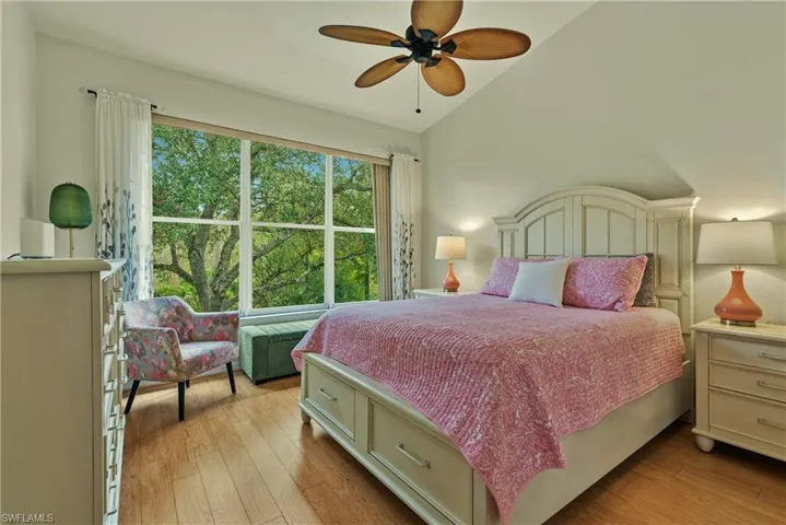 Bedroom with vaulted ceiling, light wood-style flooring, and a ceiling fan