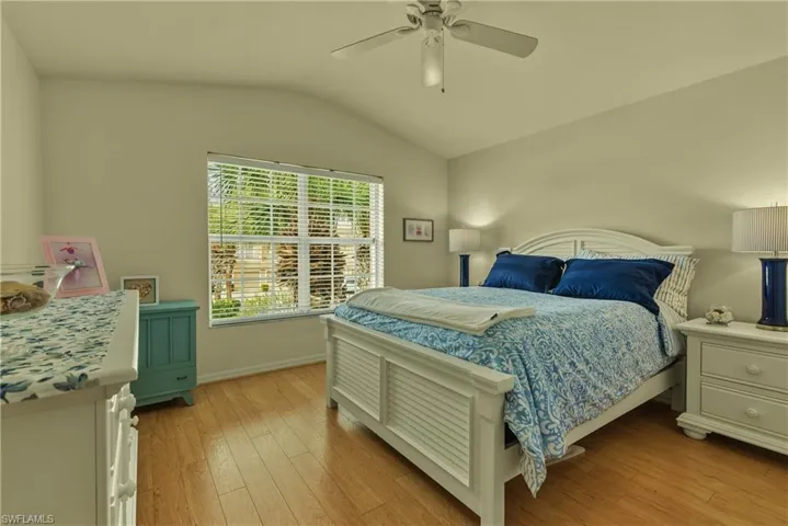Bedroom with vaulted ceiling, light wood-style flooring, and ceiling fan