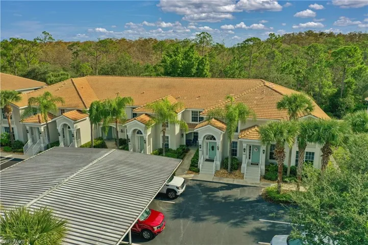 View of front of house with a tile roof, uncovered parking, and stucco siding