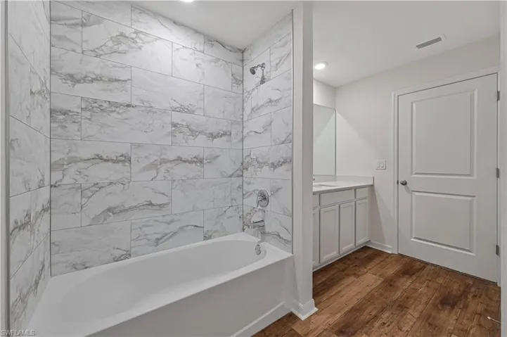 Bathroom featuring tiled shower / bath, hardwood / wood-style flooring, and vanity