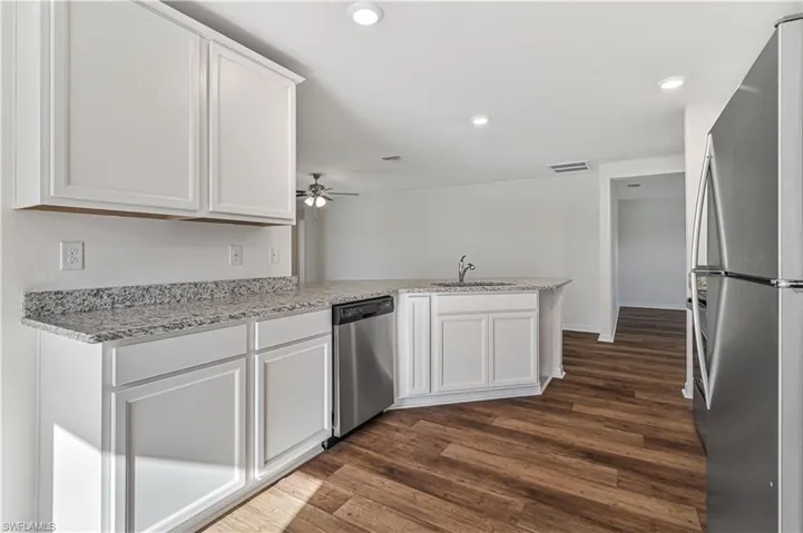 Kitchen with white cabinetry, appliances with stainless steel finishes, dark hardwood / wood-style floors, sink, and ceiling fan