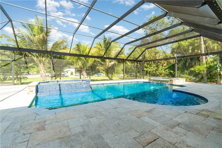View of pool with a pool with connected hot tub, a lanai, a sunroom, and a patio