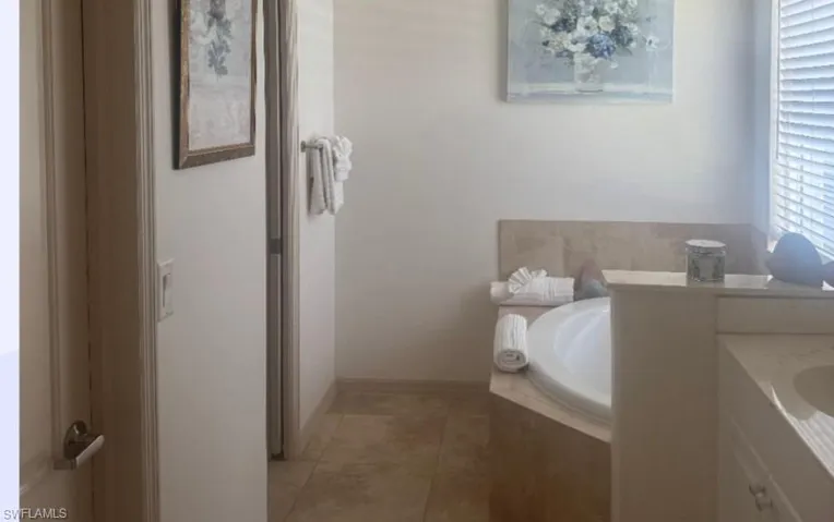 Bathroom with a garden tub, vanity, and light tile patterned floors