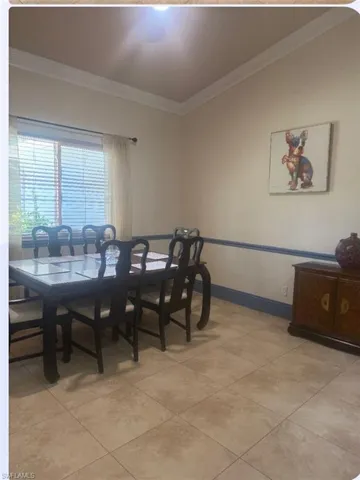 Dining area with crown molding and light tile patterned flooring