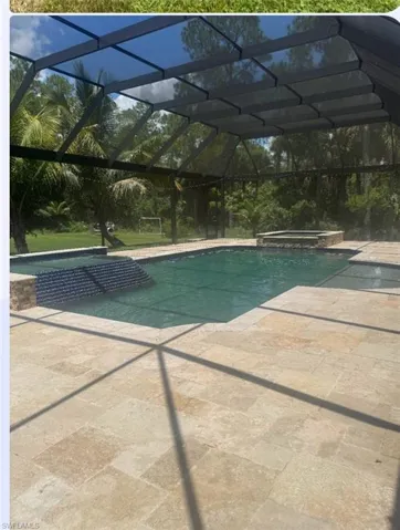 View of swimming pool featuring glass enclosure, a pool with connected hot tub, a patio, and a sunroom